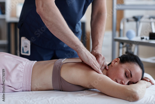 Young woman lying on couch and relaxing during massage with therapist