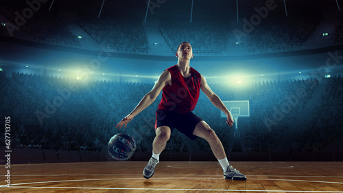 Concentrated and motivated young man, athlete, basketball player in motion during game, playing on 3D arena, stadium with flashlights. Concept of professional sport, competition, action, hobby, game.