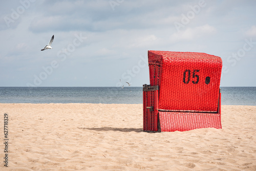 Fototapeta Naklejka Na Ścianę i Meble -  Empty red beach chair on the beach of the Baltic Sea. In the background you can see seagull.