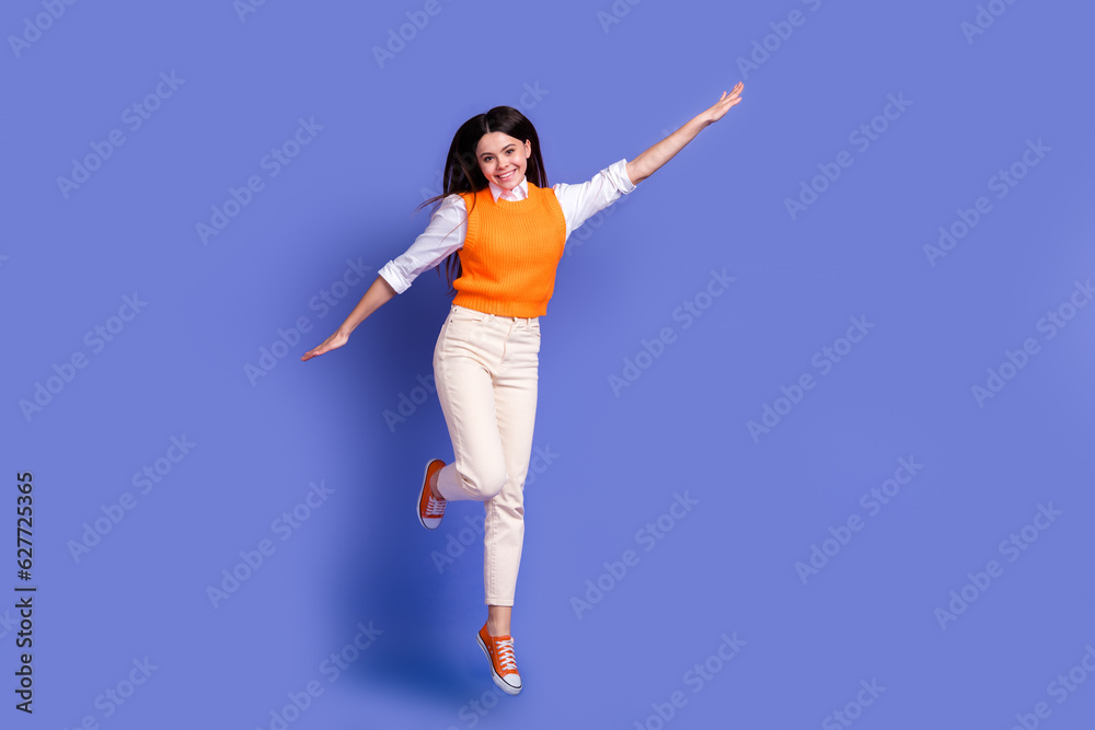 Full body length photo of overjoyed active schoolgirl flying wings jumping trampoline summer holidays isolated on violet color background