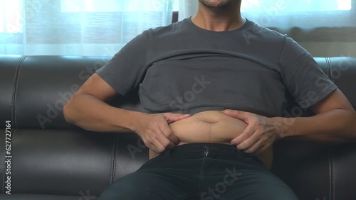 Photography Close up hand holding his belly fat with both hands.