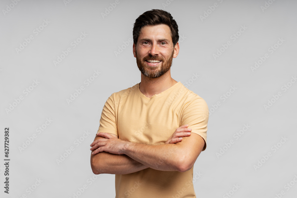 Handsome smiling bearded man wearing t shirt looking at camera isolated on grey background. Confident modern hipster with stylish hair after barbershop service