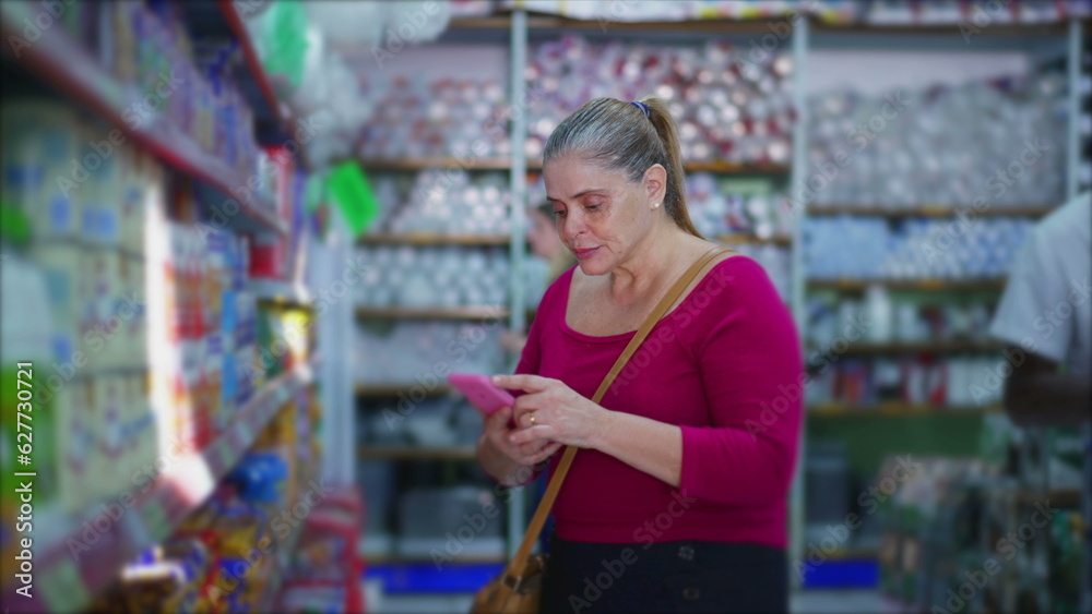 Female Shopper Cross-Checking Product Details Online Using Smartphone at Grocery Store, Illustrating Use of Technology in Shopping