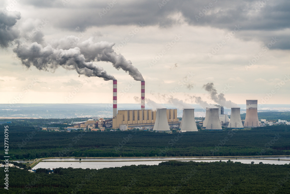 Aerial view of power plant, smoke from chimneys and open-cast coal mine in Belchatow under moody cloudy sky, Poland