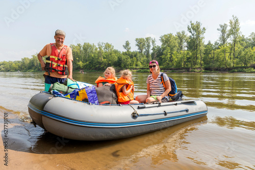 tourist family floats on an inflatable boat in life jackets on a summer day