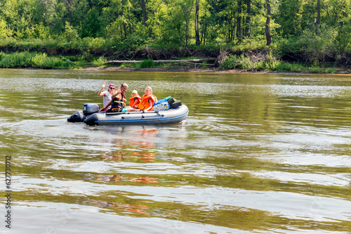 tourist family floats on an inflatable boat in life jackets on a summer day
