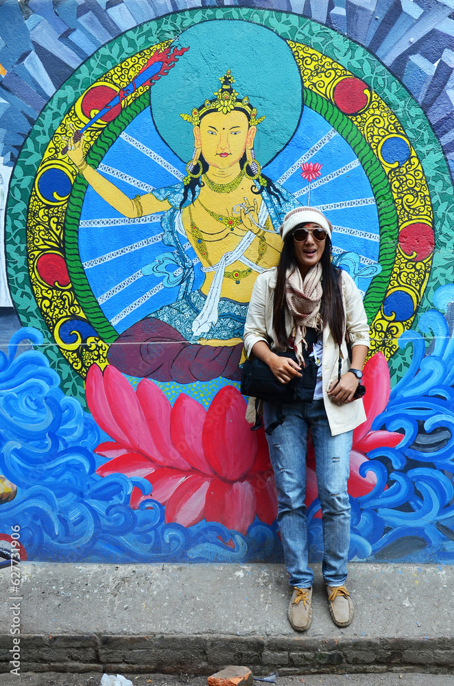 Travelers thai women journey travel visit take photo with landmark street art graffiti painting and drawing design nepalese style on antique wall at thamel city on October 29, 2013 in Kathmandu, Nepal