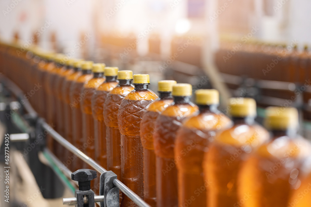 Conveyor with brown plastic beer bottles with drink alcohol, sun light. Concept modern production line brewery