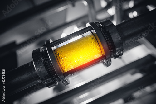 Photographie Brewing equipment for quality control, sight glass full of golden beer on stainless steel pipe