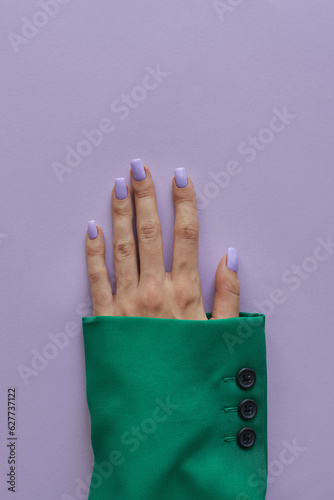 Female's hand with trendy gelish manicure with nails of purple color. Green and purple colors photo
