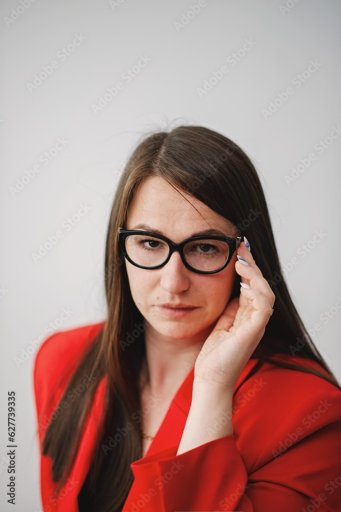 business woman in a red suit adjusts her glasses and looks sternly into the camera business woman in a red suit adjusts her glasses and looks sternly into the camera