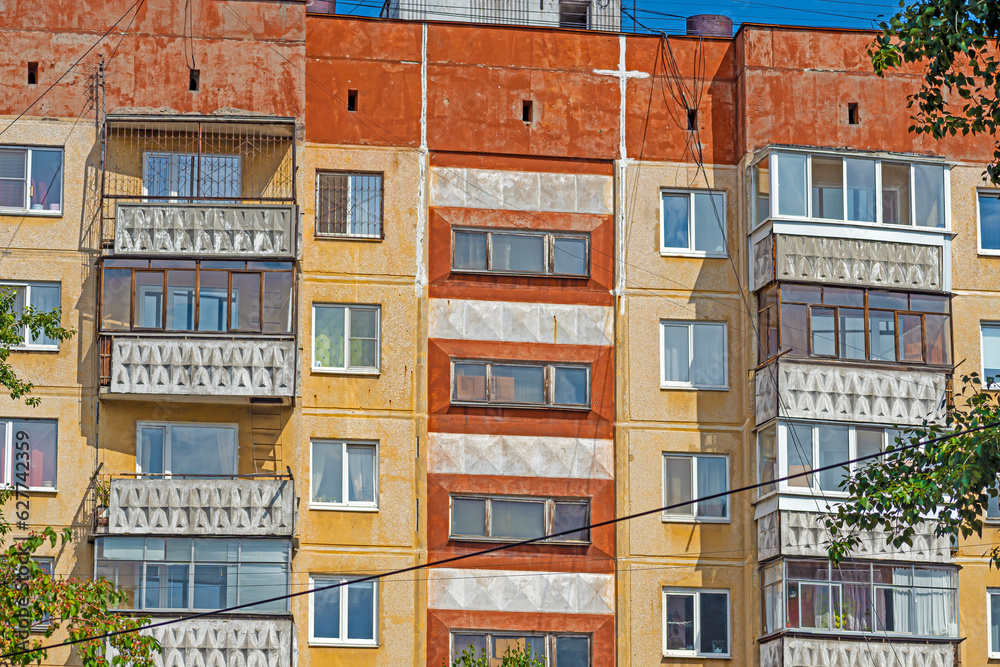 Fragment of the facade of an old panel residential building on a summer day