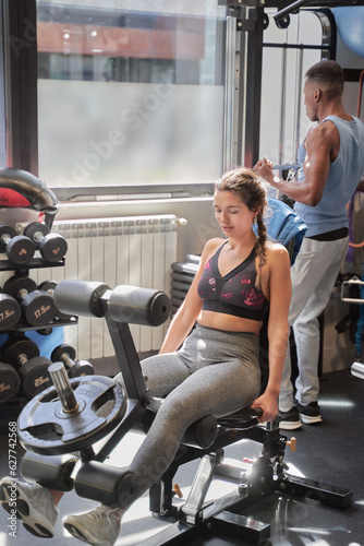 Caucasian woman exercising with quadriceps extension machines at the gym