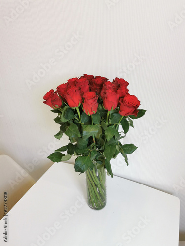 Bouquet of red roses in a glass vase on the table.