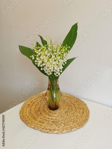 Bouquet of lilies of the valley in a vase on the table.