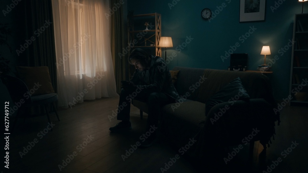 Smartphone addiction and depression. A man sits in a room in total darkness with a phone in his hands, plays an online game, a casino. Mental health concept. Smartphone addiction and depression. A man sits in a room in total darkness with a phone in his hands, plays an online game, a casino. Mental health concept.