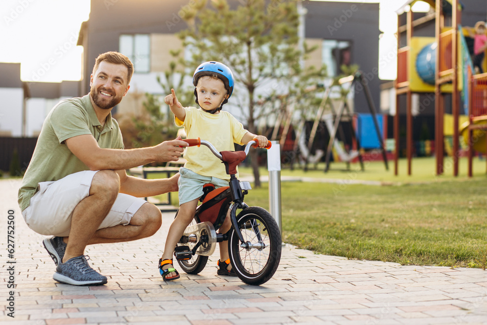 Father teaching his little son to ride a bicycle Father teaching his little son to ride a bicycle