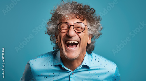 Middle-aged man laughs against a blue background.