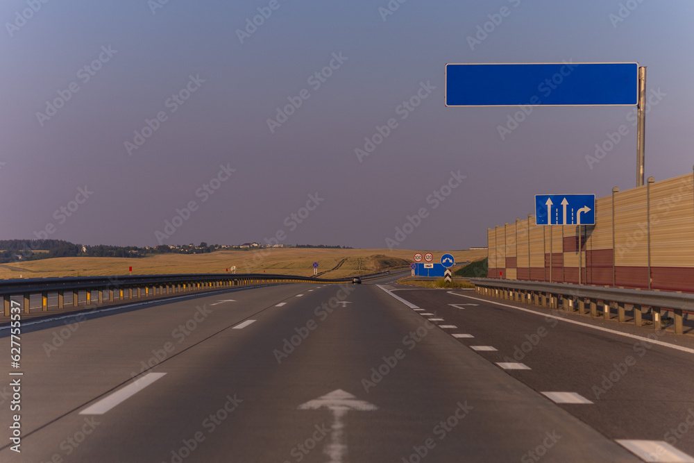Fototapeta premium highway road in the countryside, roadside and asphalt, green forest and blue sky on a sunny day 