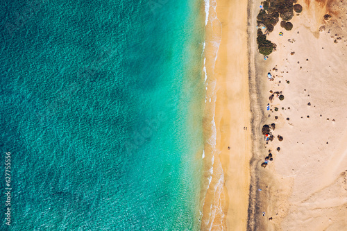 Beach with turquoise water on Fuerteventura island, Spain, Canary islands. Aerial view of sand beach, ocean texture background, top down view of sea waves by drone. Fuerteventura, Spain.
