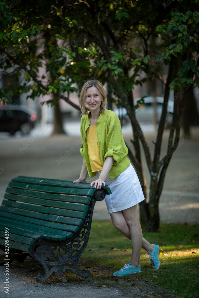 A woman in a white skirt poses in a public garden.