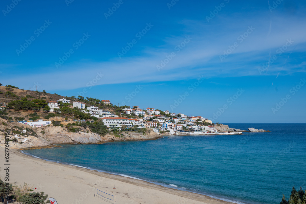 lovely greek fisher town of Armenistis in a quiet summer morning. Port with local beach in transparent clear water at Ikaria, Greece