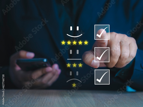 Business man hands likes customer pressing on virtual screen on smartphone with golden five star feedback icon and awesome rating for maximum rating.