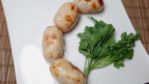 Baked thick short sausages with greens on the square dish