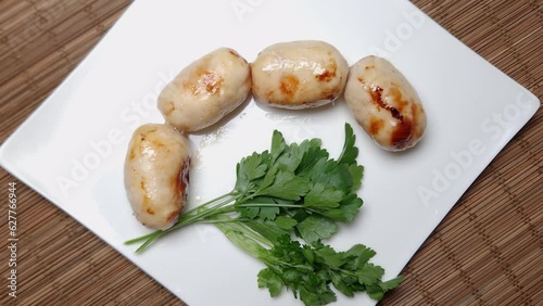 Baked thick short sausages with greens on the square dish