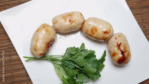 Baked thick short sausages with greens on the square dish