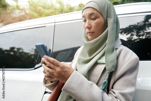 Serious muslim businesswoman reading text messages from colleagues on smartphone photo