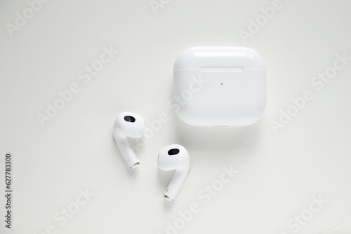 Wireless headphones and charging box on white background. Wireless bluetooth headphones in white case isolated on white background. accessories for listening music or work from home. Out of focus © tanitost