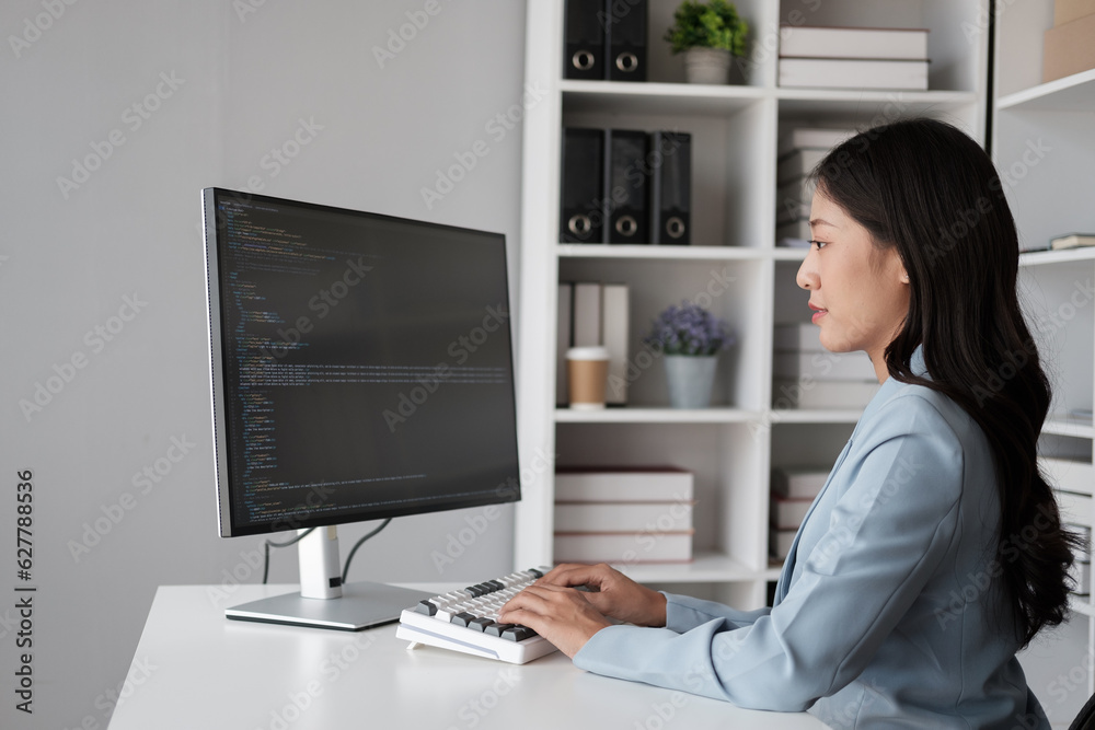 Young beautiful Asian businesswoman or programmer working in her office room with desktop computer. Young beautiful Asian businesswoman or programmer working in her office room with desktop computer.