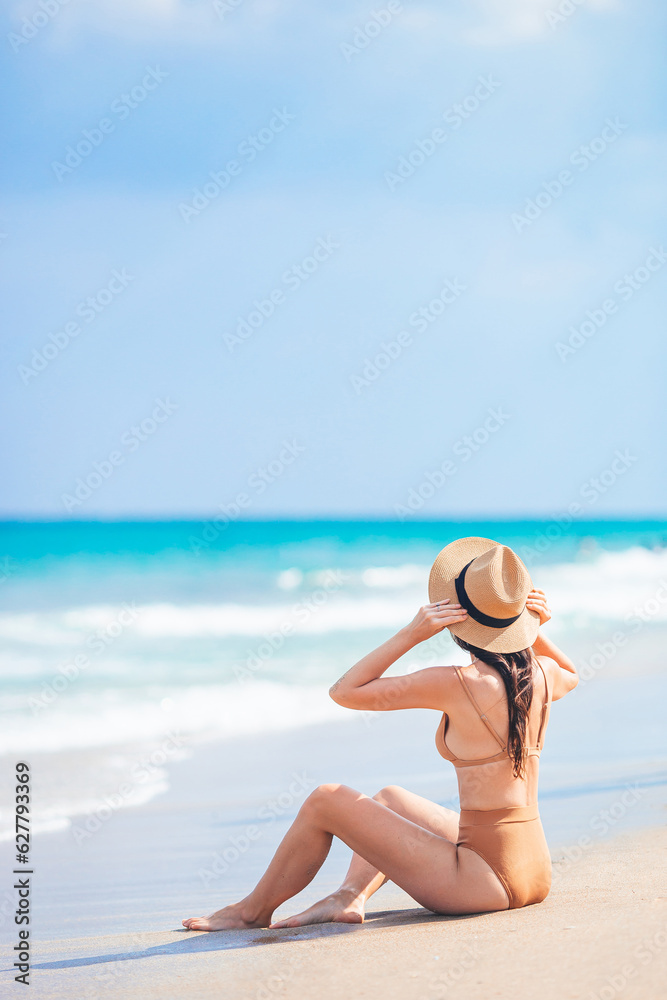 Young woman in hat on the beach enjoy her summer vacation. Woman relax on the seashore