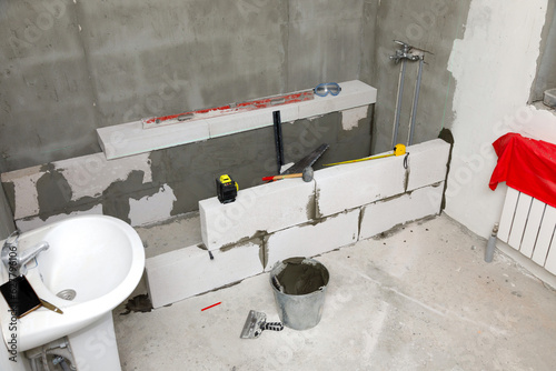 Interior of a new bathroom with the concrete blocks and construction tools. photo