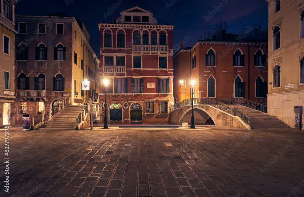 beautiful architecture of Venice, Italy, by night with a little bridge over a canal lit up by streetlight
