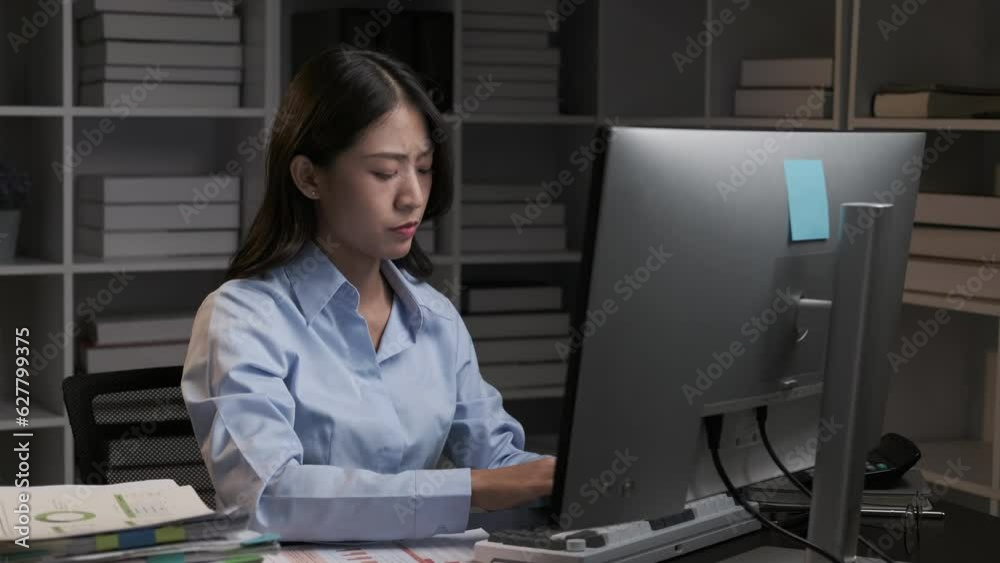 Stressful Asian businesswoman having a headache while working overtime at night, feeling tired after a long day at work. Stressful Asian businesswoman having a headache while working overtime at night, feeling tired after a long day at work.