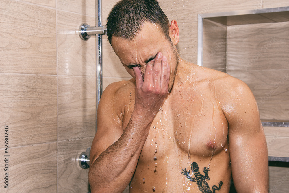 Depression and stress. Young attractive guy is crying in the shower.