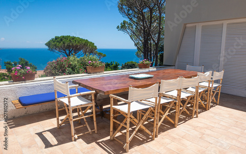 Luxury sea holidays mansion real estate, patio with table and chairs, beautiful sea view, bright summer day