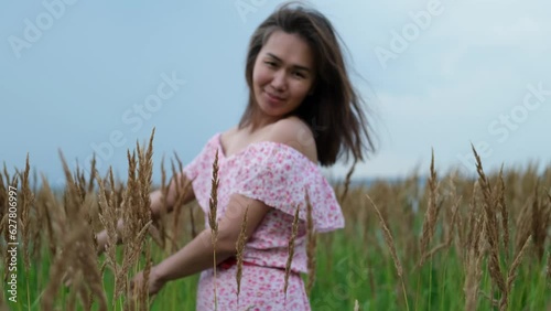 A happy free farmer girl walks through the tall grass near the lake in summer. Agriculture childhood dream concept. photo