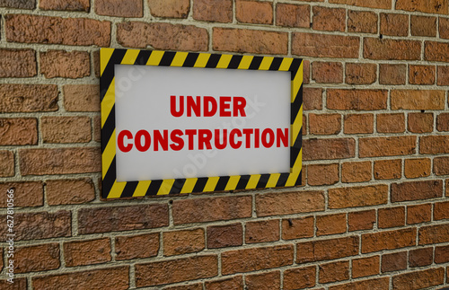 Under construction sign on a brick wall.