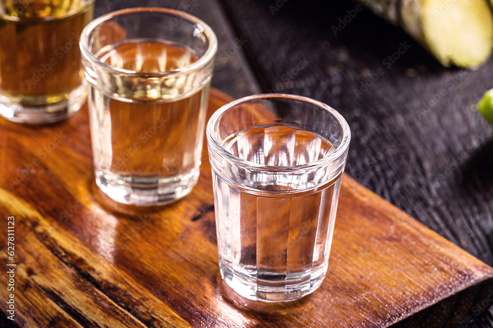 cups of cachaça, with sugar cane in the background, a Brazilian