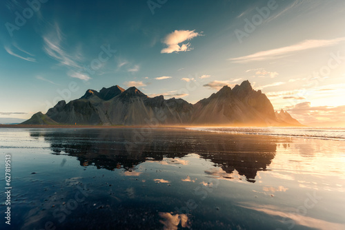 Sunrise over Vestrahorn mountain with reflection on black sand beach in summer at Iceland photo