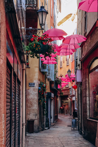 Fototapeta Naklejka Na Ścianę i Meble -  Grasse, France - July 23, 2023: Famous pink umbrellas decorating the central streets of Grasse