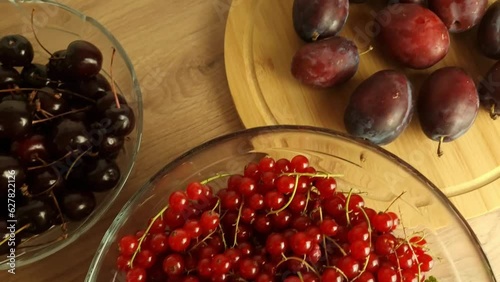 A still life ripe red detox currants, cherries and plums on wooden table, overhead view