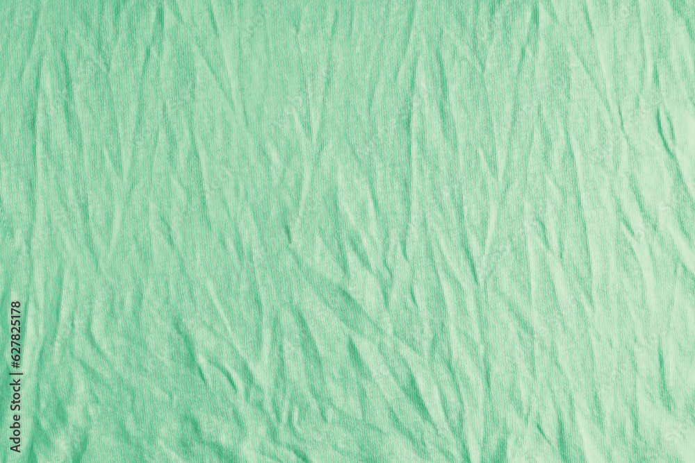 Wrinkled, crumpled green fabric texture background. Wrinkled and creased abstract backdrop of cotton jersey textile, wallpaper with copy space, top view. Wrinkled, crumpled green fabric texture background. Wrinkled and creased abstract backdrop of cotton jersey textile, wallpaper with copy space, top view.