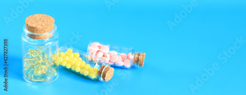 Vitamins in glass bottles on a blue background, copy space. Vitamins, painkillers, healthcare, health pills and dietary supplements. Vitamin B complex and Omega 3 photo