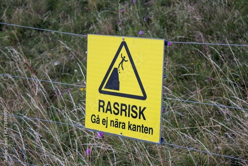 A yellow sign on a fence