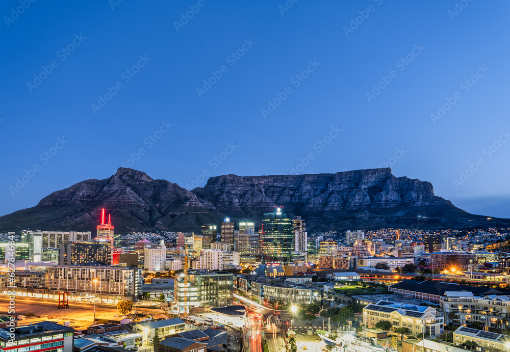 Wide angle shot of Cape town City buildings and streets lit up at night with the table mountain in the background, Cape Town, South Africa