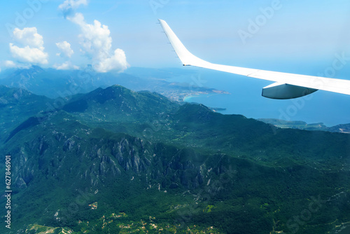 beautiful view of the coast of Montenegro from the height of an airplane flight, mountains and sea, blue sky with soft clouds and an airplane wing, the concept of travel